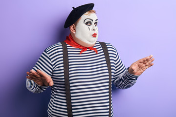 talented actor with raised arms showing pantomime. close up portrait, isolated blue background,...