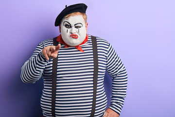 angry sad artist stretching his two fingers, having fun, isolated blue background, studio shot.copy...