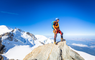 Naklejka na ściany i meble Alpinist mountaineer standing rock cliff mountain summit.