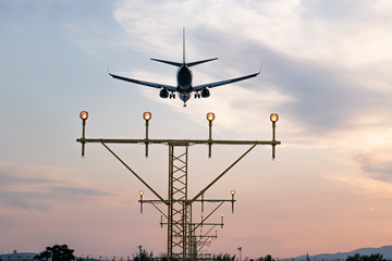 Aircraft during the approach procedure at sunset overflying the runway lights. Precision approach ILS-guided landing.