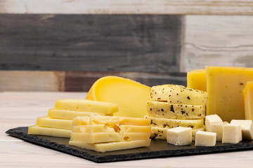 Assortment of various types of cheese on a black stone plate. copy space