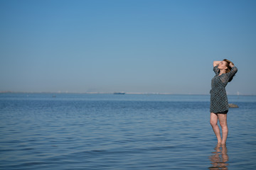 Attractive plus size woman in chiffon dress enjoys the shiny water in the blue sea