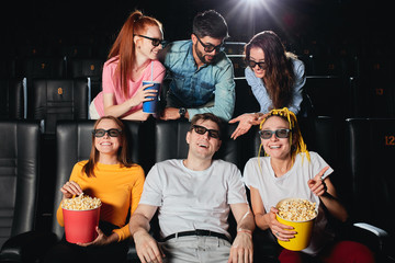Multiethnic cheerful audience sitting at the cinema and watching movie, students get pleasure from...