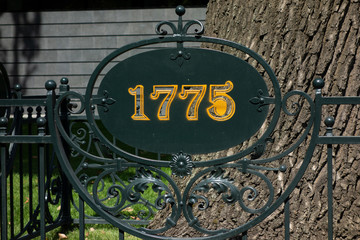 1775 year sign on metal forging fence in front of big tree. Information table placard or signboard in park or botanic garden to designate remarkable date or event