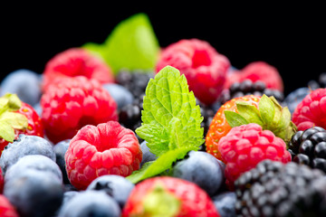 Berries. Various colorful berries background. Strawberry, raspberry, blackberry, blueberry closeup over black. Healthy eating