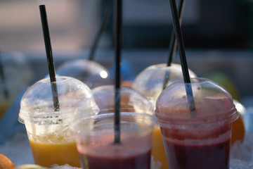 tasty frozen orange and red fresh juices in plastic cups in the sun