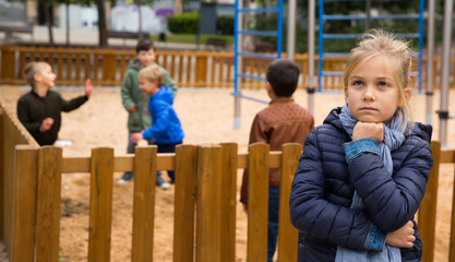 Obraz premium Upset girl on the background of playing children