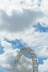 Ferris wheel on the blue cloudy sky. Background concept of happy holidays time.