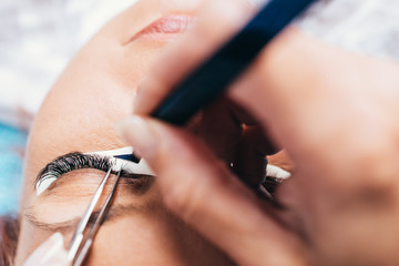 Beautiful middle age woman at eyelash extension procedure. Cosmetics and body care close up shot.