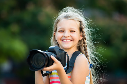 admiring female child taking pictures with camera in park