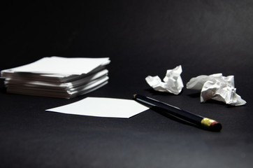 White square stickers crumpled pieces of paper of the same size on a black background with a simple pencil