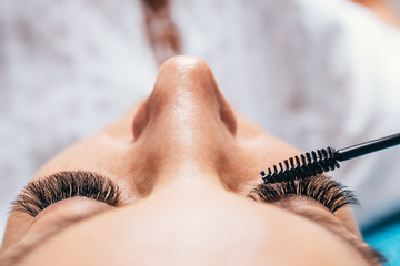 Beautiful middle age woman at eyelash extension procedure. Cosmetics and body care close up shot.