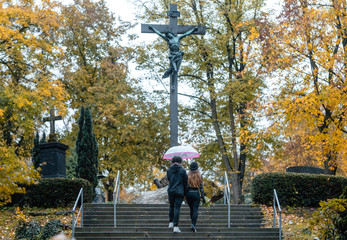 Man and woman walking up steps on cemetery towards a cross