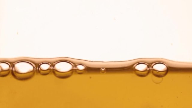 Close-up, bubbles attract each other and burst. Isolated on white background.