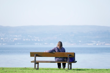 Single lady lonely on park bench at the sea enjoy peace and quiet for mindfulness meditation
