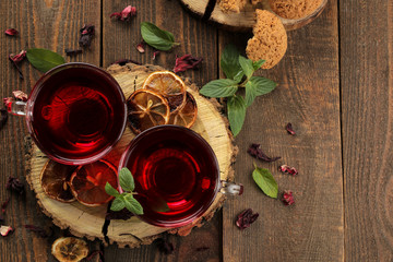 Hot red karkade tea with honey and mint. Autumn or winter soft drink. on a brown wooden table. view from above