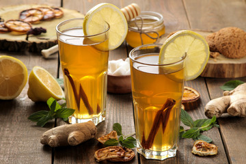 Tea with lemon and a cinnamon stick with ginger and mint in glass cups on a brown wooden table. a warming drink. Autumn or winter drink.
