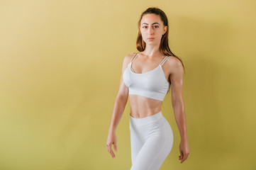 Portrait of athlete sexy girl in white sportswear posing in gym