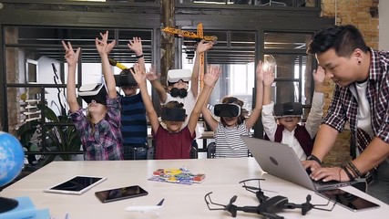 Korean teacher with group young pupils with laptop and VR headsets during a computer science class