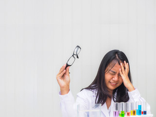 asia science woman wearing white coat uniform holding glasses feeling headache with copy space blank background.