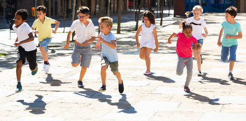 Group of joyful children running down the city street