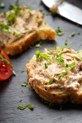 Bread with pork pate and herbs on a dark slate