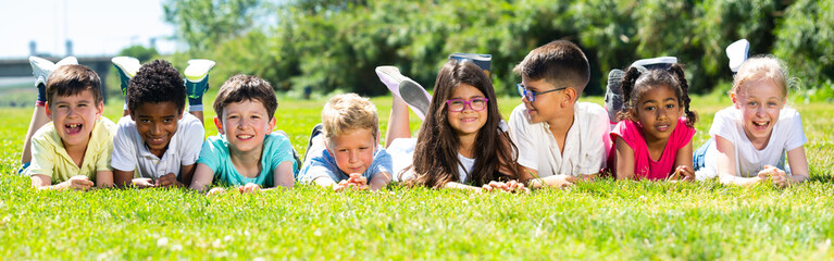 Team of friends children resting on grass together in park