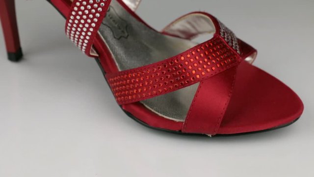 Macro, close-up. Slow rotation of red women's sandals on a white background.