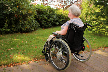 lonely paralyzed woman in a wheelchair sits outdoors and looks at the nature