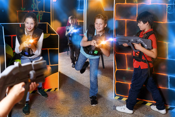 Fototapeta na wymiar Glad teens aiming laser guns at other players