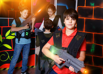 Fototapeta na wymiar Portrait of preteen boy with laser pistol posing in laser tag la