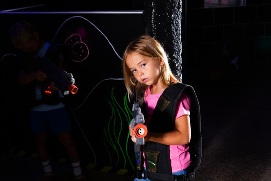 Portrait of teenager girl with laser gun having fun on dark lasertag arena