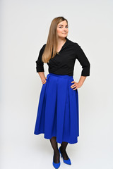Fototapeta premium Full length vertical portrait of a cute brunette middle-aged manager woman with beautiful curly hair in a business suit and blue skirt on a white background. Beauty, brightness, smile.