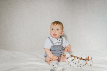 Portrait of funny baby sitting on white bed in bedroom