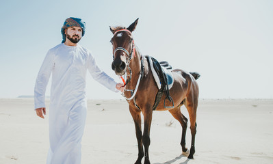 Arabian man with traditional clothes riding his horse
