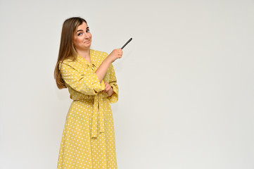 Portrait of a cute middle-aged manager brunette woman with beautiful curly hair in a yellow dress on a white background with a pen in her hands. Beauty, brightness, smile.