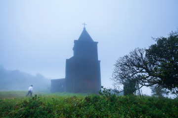 Male Khmer walking toward the abandoned ancient church in the mist.