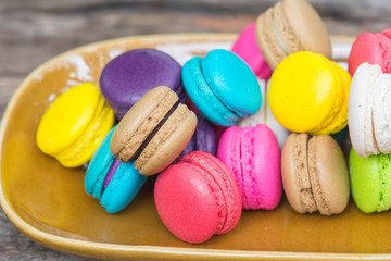 Colorful Macaroons in dish on wooden table