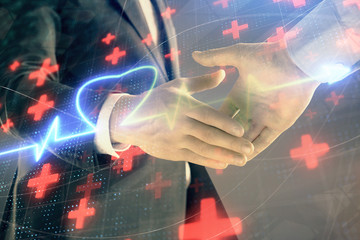 Multi exposure of heart hologram on abstract background with two men handshake. Concept of medical education