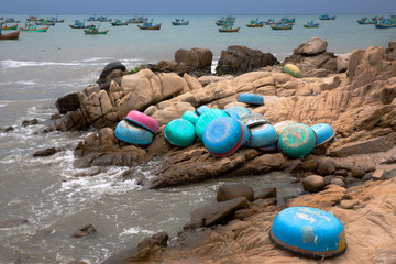 Coracles on the shoreline with larger fishing boats in the distance, Vietnam