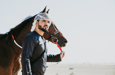 Arabian man with traditional clothes riding his horse