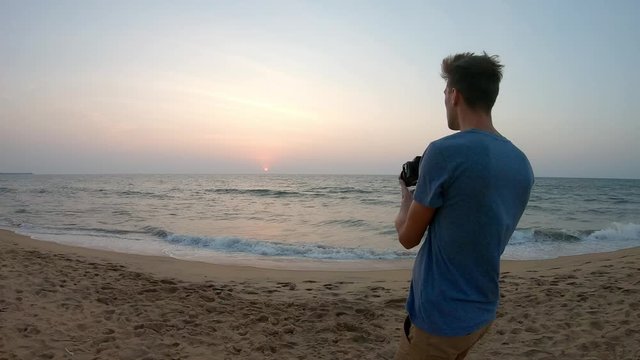 Caucasian boy is making photo at the Srilankian sea