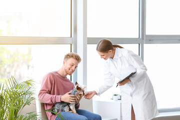 Man with his dog visiting veterinarian in clinic