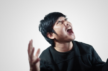 Young man's face Portrait of a young man screaming and looking up above while standing against a gray background.