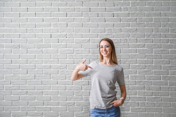 Woman pointing at her t-shirt against brick wall
