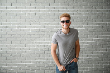 Man in stylish t-shirt near brick wall