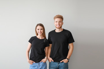 Couple in stylish t-shirts on light background