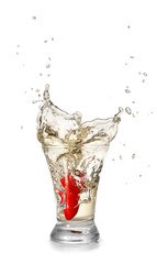 Dropping of chili pepper into glass with tasty tequila on light background