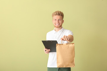 Handsome worker of food delivery service on color background