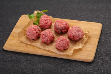 Raw meatball over wooden background